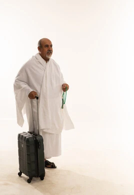 رجل سعودي بملابس الإحرام مع حقيبة سفر