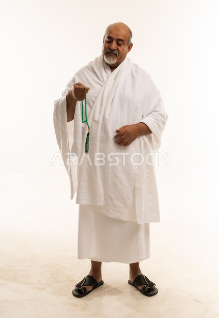 رجل سعودي بملابس الإحرام يمسك بسبحة