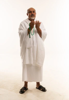 رجل عربي مسن بملابس الإحرام يدعو ويحمل مسبحة