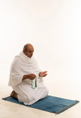 Elderly Saudi Man in White Ihram Praying with Misbaha