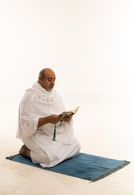 Saudi Pilgrim in Ihram Reading Quran on Prayer Mat