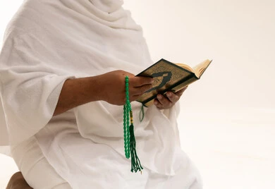 رجل سعودي بملابس الإحرام يقرأ القرآن الكريم