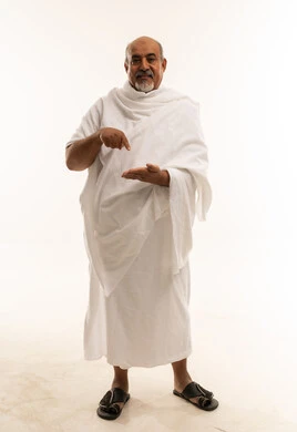 رجل سعودي مسن بملابس الإحرام يشير بيده