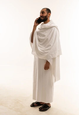 رجل بملابس الإحرام يتحدث عبر الهاتف المحمول