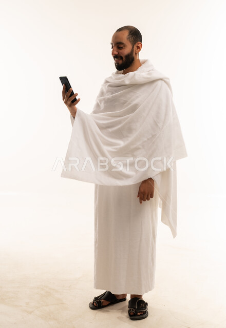 رجل سعودي بملابس الإحرام يستخدم الهاتف الذكي
