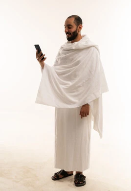 رجل سعودي بملابس الإحرام يستخدم الهاتف الذكي