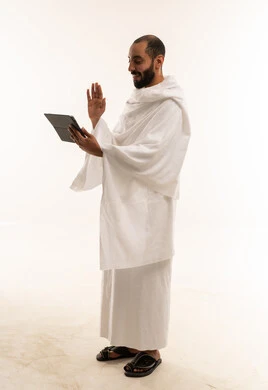 رجل سعودي بملابس الإحرام يستخدم جهاز لوحي
