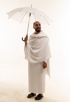 رجل سعودي بملابس الإحرام مع مظلة بيضاء
