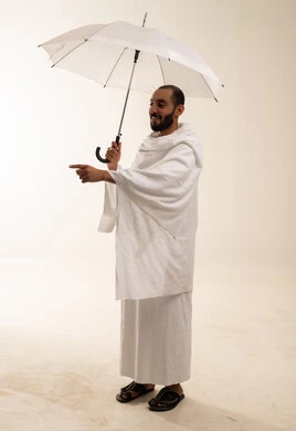 رجل سعودي بملابس الإحرام يحمل مظلة في الاستوديو