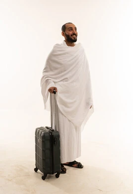 رجل سعودي بملابس الإحرام مع حقيبة سفر