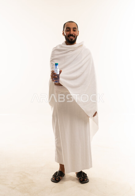 رجل سعودي بملابس الإحرام يحمل زجاجة ماء