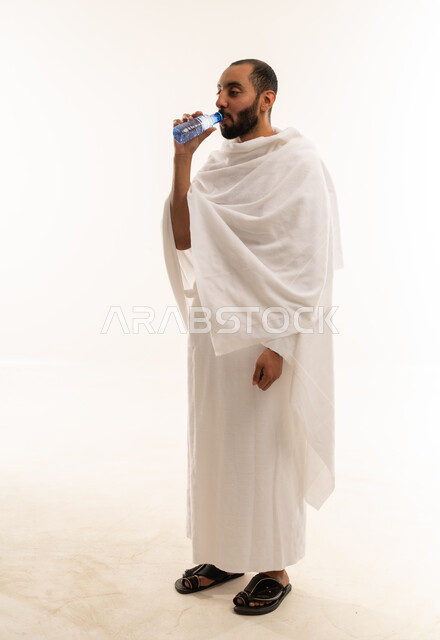 رجل سعودي بملابس الإحرام يشرب الماء