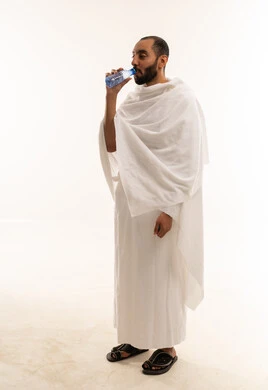 رجل سعودي بملابس الإحرام يشرب الماء