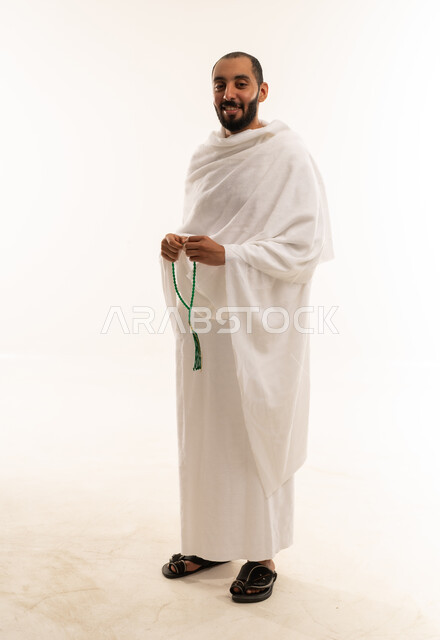 رجل سعودي بملابس الإحرام يحمل مسبحة خضراء
