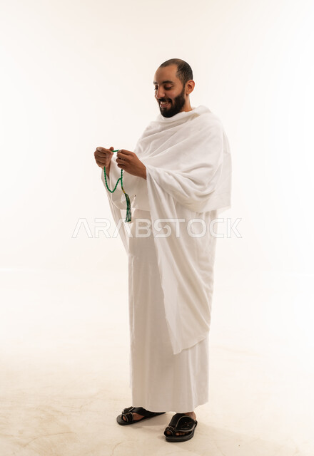 رجل سعودي بملابس الإحرام يمسك مسبحة خلفية بيضاء