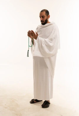 رجل مسلم بملابس الإحرام يدعو ويحمل سبحة