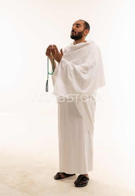 رجل سعودي بملابس الإحرام يدعو بالمسبحة