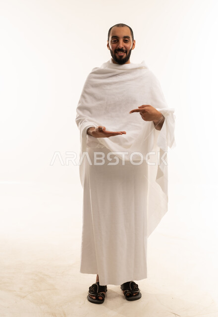 رجل سعودي بملابس الإحرام يشير بيديه خلفية بيضاء