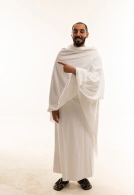 رجل سعودي بملابس الإحرام يشير على خلفية بيضاء