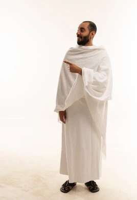 رجل سعودي بملابس الإحرام يشير على خلفية بيضاء