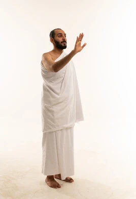 رجل سعودي بملابس الإحرام يمد يده في الاستوديو