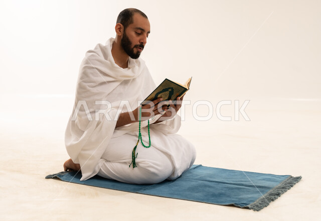 رجل سعودي بملابس الإحرام يقرأ القرآن الكريم
