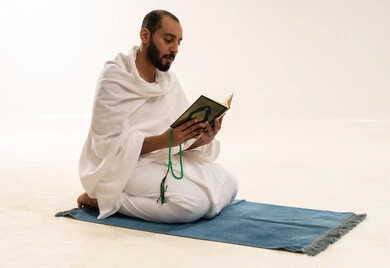 رجل سعودي بملابس الإحرام يقرأ القرآن الكريم