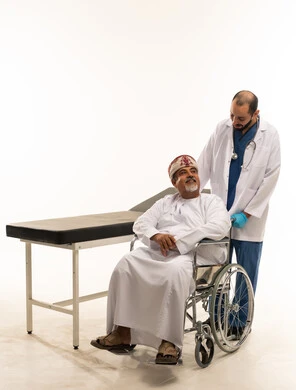 مريض عُماني على كرسي متحرك مع طبيب خلفية بيضاء