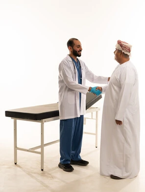 طبيب عماني يصافح مريضاً في عيادة طبية