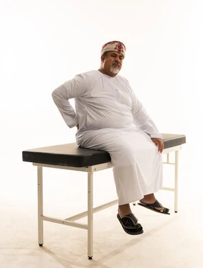 رجل عماني يعاني من ألم الظهر على طاولة فحص طبي