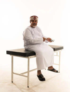 رجل عماني يمسك نقودا على سرير الفحص الطبي