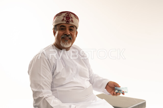 Omani Senior Man Holding Medication Box in Studio