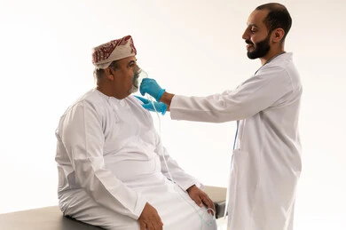 طبيب عماني يضع قناع أكسجين لمريض مسن