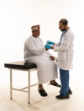 فحص طبي لمريض عماني مع طبيب بخلفية بيضاء فحص طبي لمريض عماني مع طبيب بخلفية بيضاء