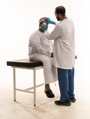 طبيب عماني يفحص عين مريض مسن في عيادة طبية