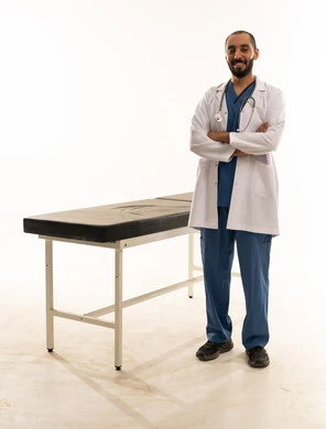 طبيب سعودي يرتدي معطفاً أبيض وملابس طبية زرقاء