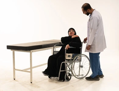طبيب عربي مع مريضة مسنة على كرسي متحرك