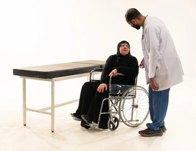 طبيب سعودي يتحدث مع مريضة مسنة على كرسي متحرك