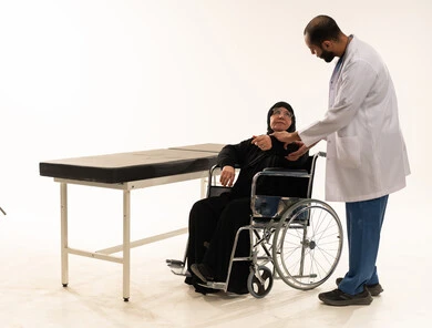 طبيب سعودي يفحص مريضة مسنة على كرسي متحرك