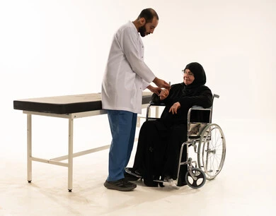 طبيب سعودي يفحص امرأة مسنة على كرسي متحرك