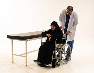 Arab Doctor Examining Elderly Patient in Wheelchair