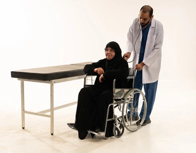Saudi Doctor Examining Elderly Patient in Wheelchair