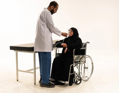 طبيب سعودي يعالج مريضة مسنة على كرسي متحرك