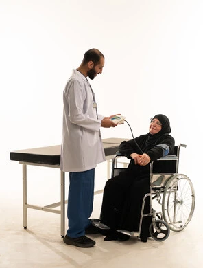 طبيب عربي يفحص مريضة مسنة على كرسي متحرك