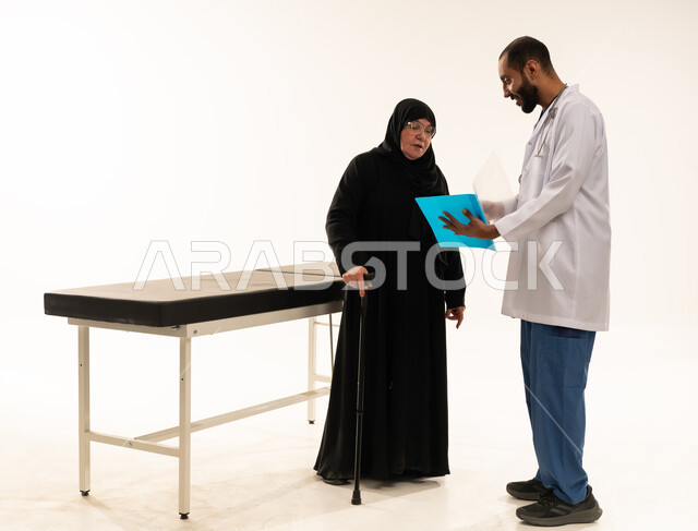 طبيب سعودي يستعرض تقرير طبي مع مريضة مسنة