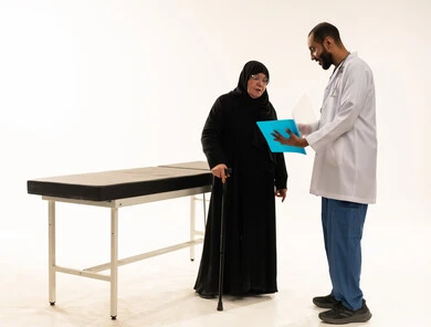 طبيب سعودي يستعرض تقرير طبي مع مريضة مسنة