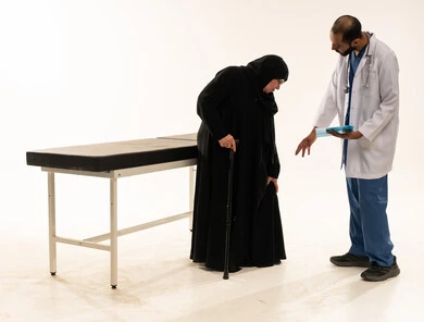 طبيب سعودي يساعد امرأة مسنة في عيادة طبية