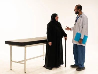 Saudi Doctor Consulting Elderly Woman in Medical Office