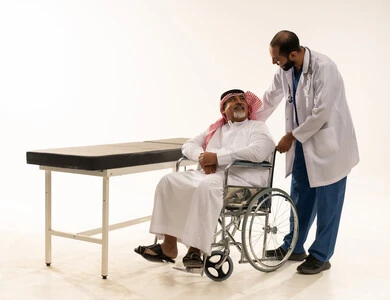 طبيب سعودي يساعد مريض على كرسي متحرك