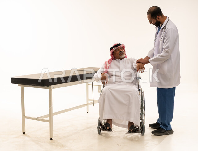 طبيب سعودي يفحص مريضاً مسناً على كرسي متحرك
